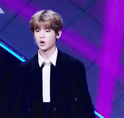 a young man in a suit and tie is standing on a stage .