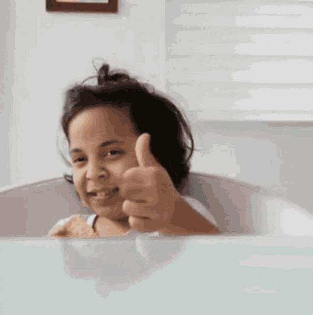 a young girl is eating a potato chip while sitting at a table