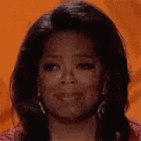 a close up of oprah winfrey 's face with her mouth open against an orange background .