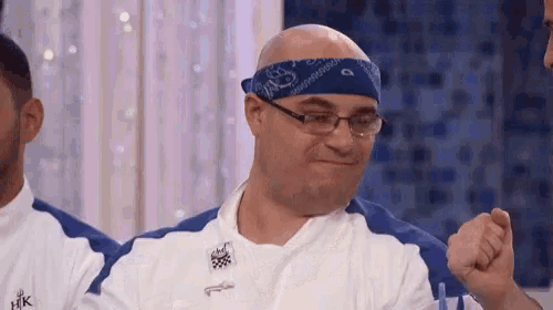 a man wearing a bandana and glasses is sitting at a table .