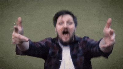 a man with a beard and a plaid shirt is pointing at the camera