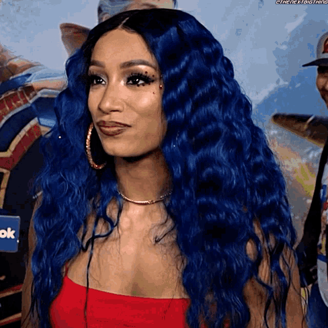 a woman with long blue hair is wearing a red top and hoop earrings