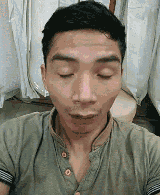 a man in a green shirt is taking a selfie with his eyes closed .