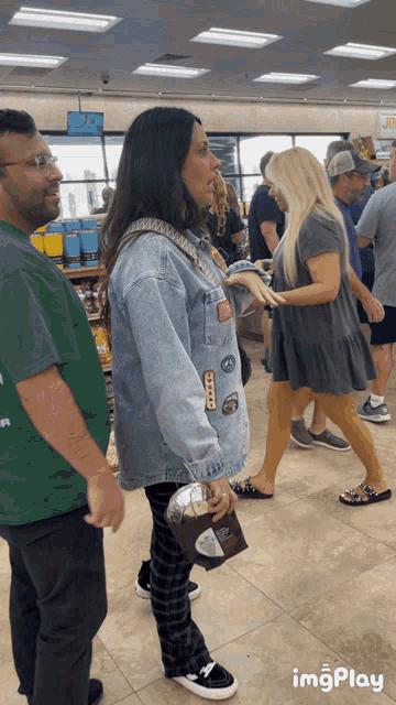 a woman in a denim jacket holds a cup of coffee in a store