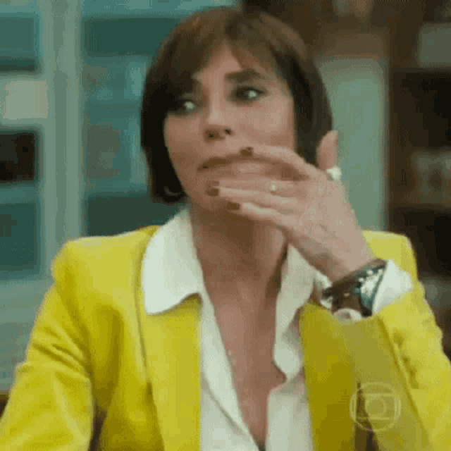 a woman is wearing a yellow jacket and covering her mouth with her hand .