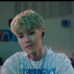 a young man wearing headphones and a plastic jacket is sitting in a room .