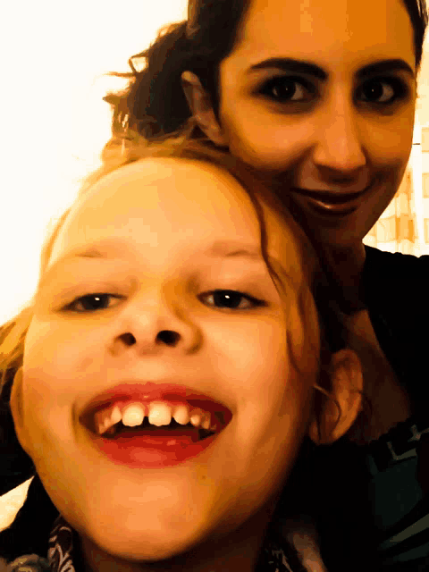 a woman and child are posing for a picture and smiling