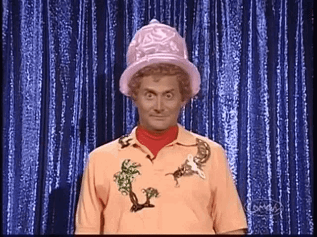 a man is wearing a pink hat and an orange shirt .