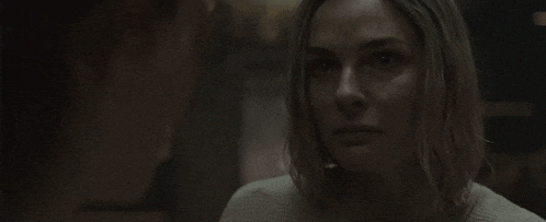 a woman is sitting in a dark room looking at the camera .
