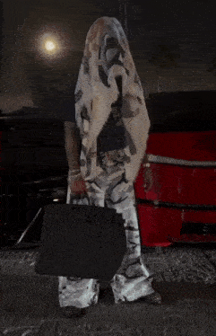 a man in camo pants holds a black purse