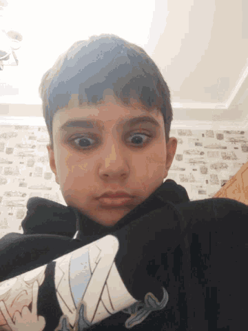 a young boy wearing a black shirt with a cartoon character on it looks at the camera