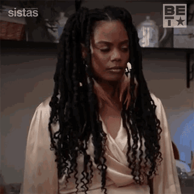 a woman with dreadlocks is wearing a satin robe and looking down .