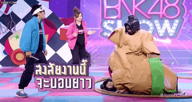 a sumo wrestler is on a stage in front of a bnk48 show