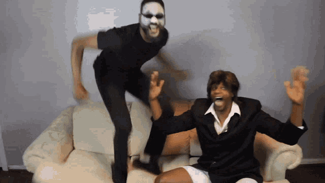 a man in a white mask is jumping in the air next to another man in a suit
