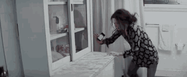 a woman is looking at her phone in a bathroom .