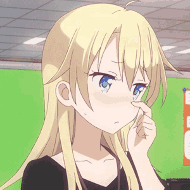 a girl with blonde hair and blue eyes is touching her nose with her finger