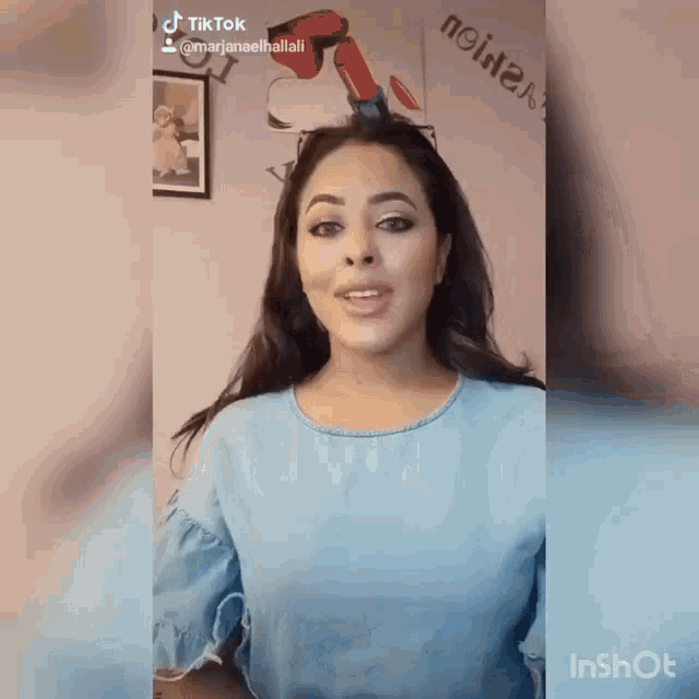 a woman in a blue shirt is making a tiktok video