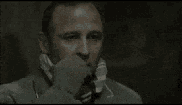 a man wearing a suit and tie is talking on a telephone .
