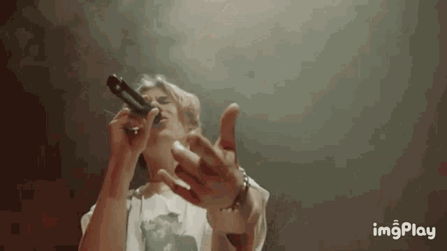 a woman is singing into a microphone on a stage with her hands outstretched .