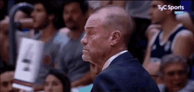a man in a suit is watching a basketball game on tv