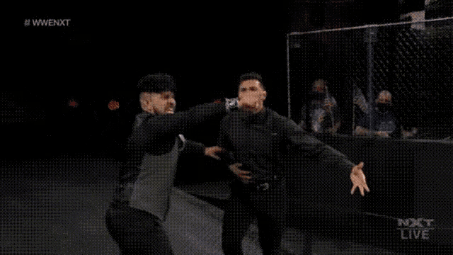 a couple of men are standing next to each other on a stage in a dark room .