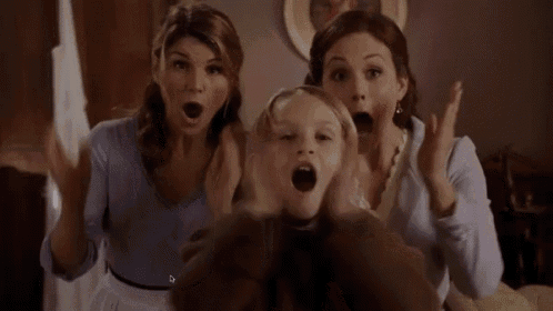 two women are sitting on a couch with their mouths open