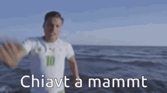 a man in a white shirt with the number 10 on it is standing on the beach .