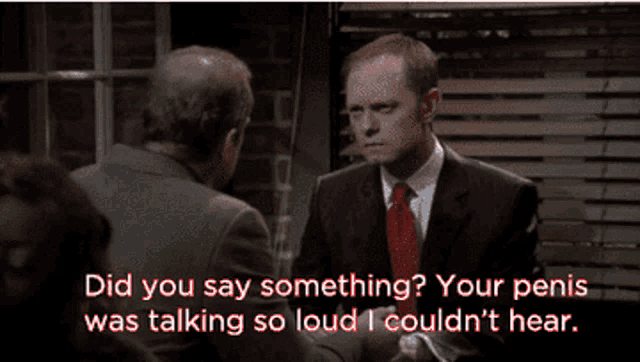 a man in a suit and red tie talking to another man