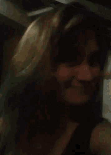 a woman taking a selfie in a dark room with her hair blowing in the wind
