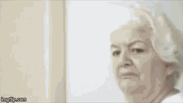 an elderly woman with white hair is standing in front of a door .