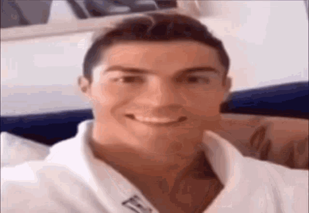 a man in a white robe is smiling for the camera while sitting on a couch .