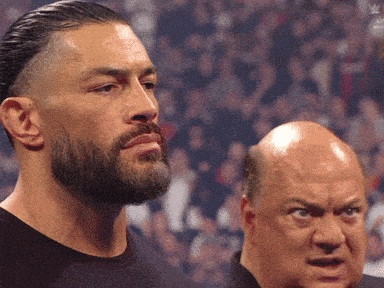 a man with a beard is standing next to a bald man with a serious look on his face