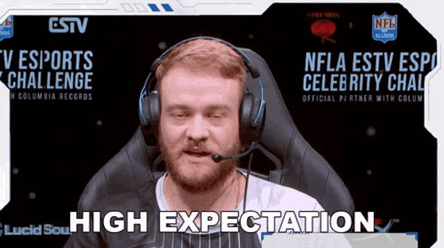a man wearing headphones is sitting in front of a screen that says high expectation