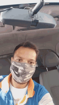 a man wearing a nike face mask looks at the rear view mirror