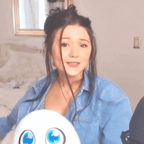 a woman in a blue shirt is holding a stuffed animal