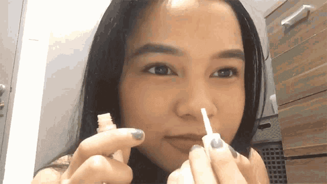 a woman is holding a small white bottle in front of her face