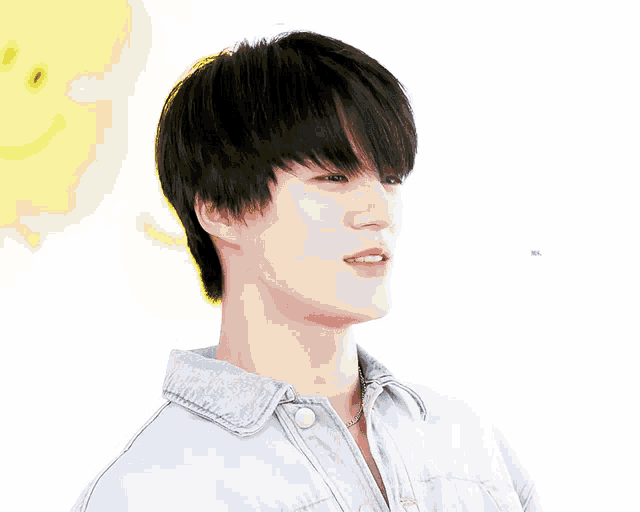a young man with black hair is wearing a denim shirt