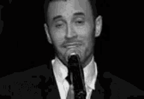 a man in a suit and tie is standing in front of a microphone .