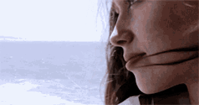 a close up of a woman looking out at the ocean