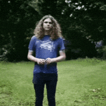 a man with long curly hair wearing a blue shirt with a duck on it
