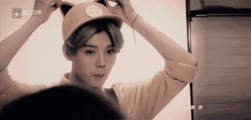 a young man is wearing a cat ear hat and looking at himself in the mirror .