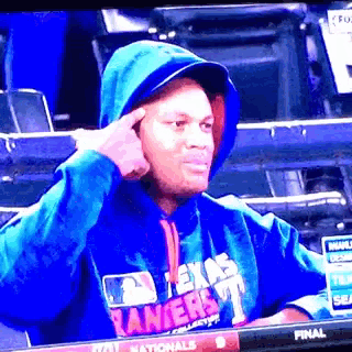a man wearing a blue texas rangers sweatshirt is sitting in the stands