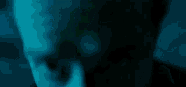 a close up of a person 's face in a dark room in a blue light .