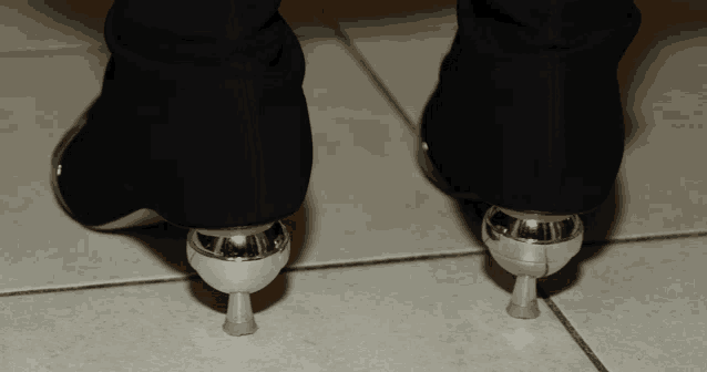 a pair of black shoes with silver heels are on a tiled floor