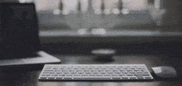 a keyboard and mouse sit on a desk in front of a window