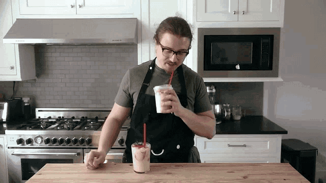 a man in an apron drinks a milkshake with a straw