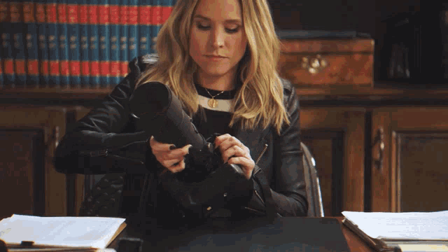 a woman sitting at a desk with a sign that says veronica mars