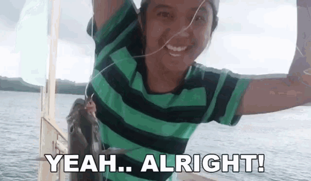 a young girl is holding a fish in her hands and smiling while standing on a boat .