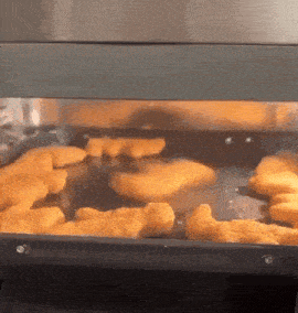 chicken nuggets are being cooked in a stainless steel oven