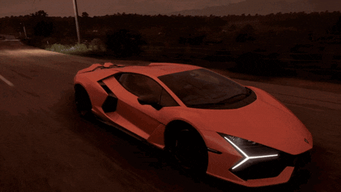 an orange sports car is driving down a dark road